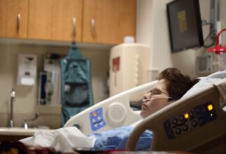 Intensiv-Versorgung eines Patienten, der in einem Klinikbett liegt und über die Nase mit Sauerstoff versorgt wird.