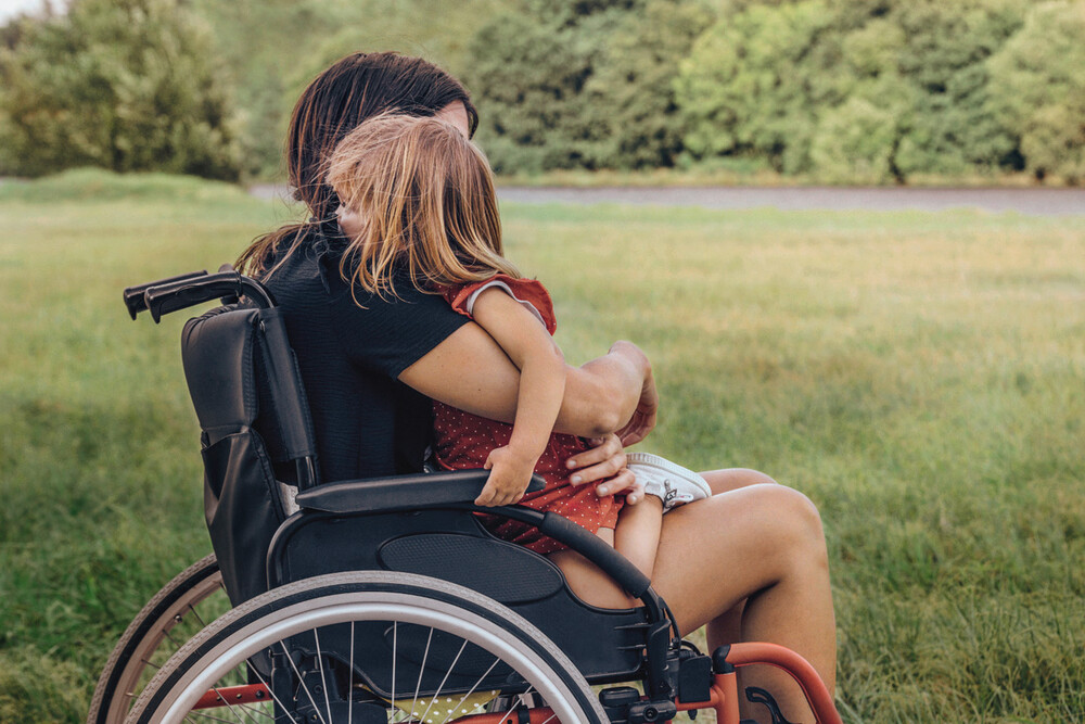Frau im Rollstuhl mit Kind auf dem Schoß